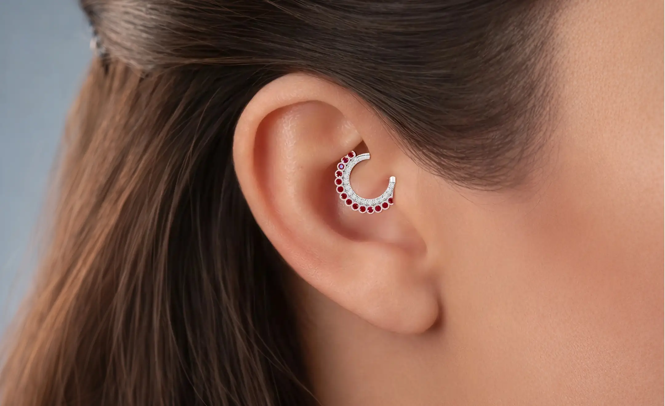 Gros plan de l'oreille d'une femme portant une combinaison d'anneaux daith rubis et diamant sur le piercing daith