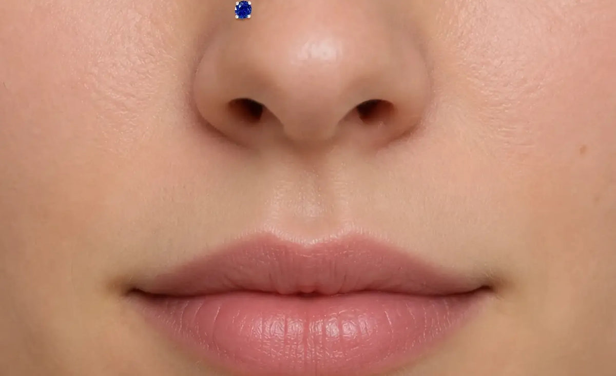 Gros plan extrême du bas du visage d'une personne montrant un stud nostril saphir bleu sur la narine gauche
