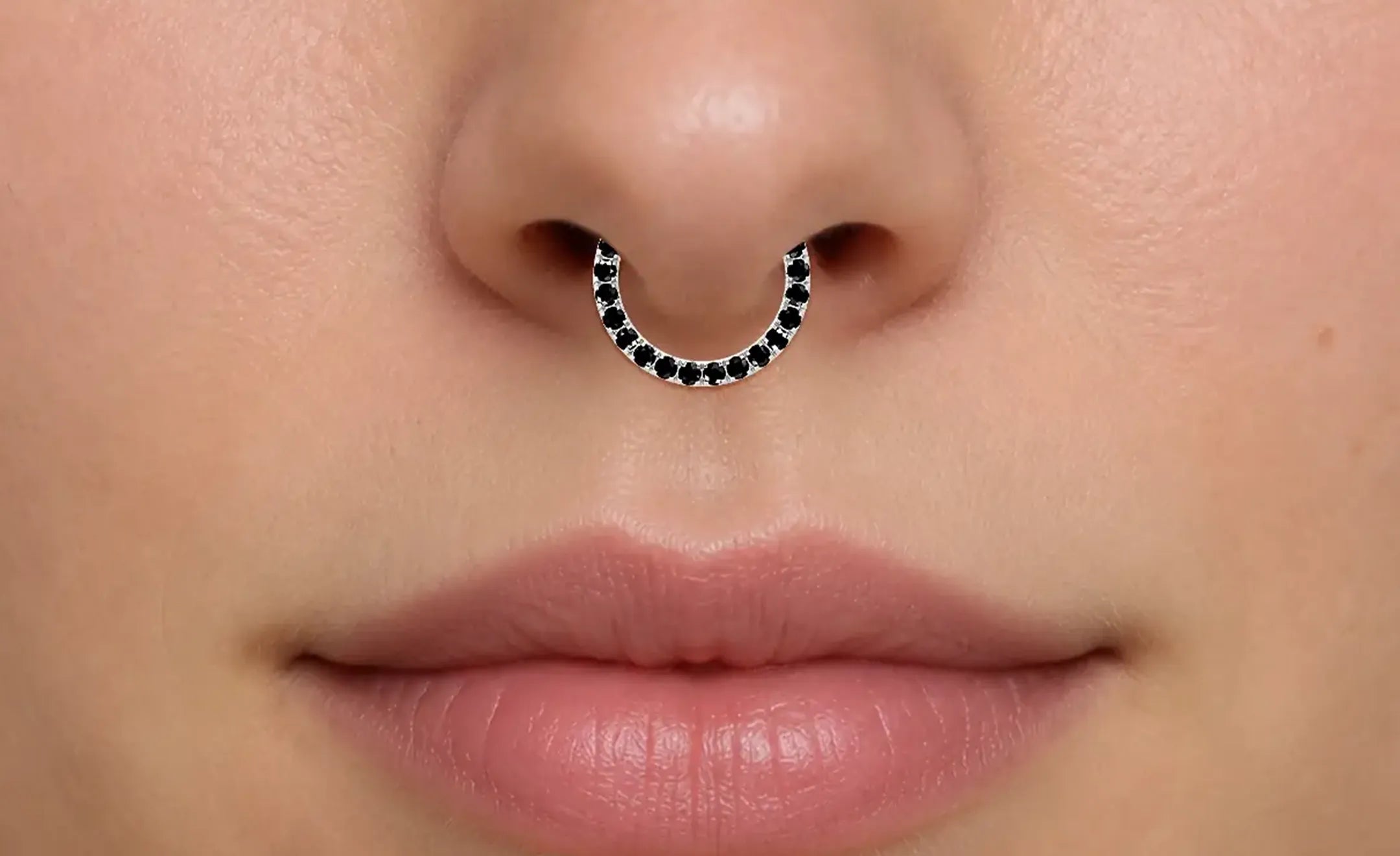 A close-up of a person's nose wearing black diamond nose ring worn on the septum piercing 