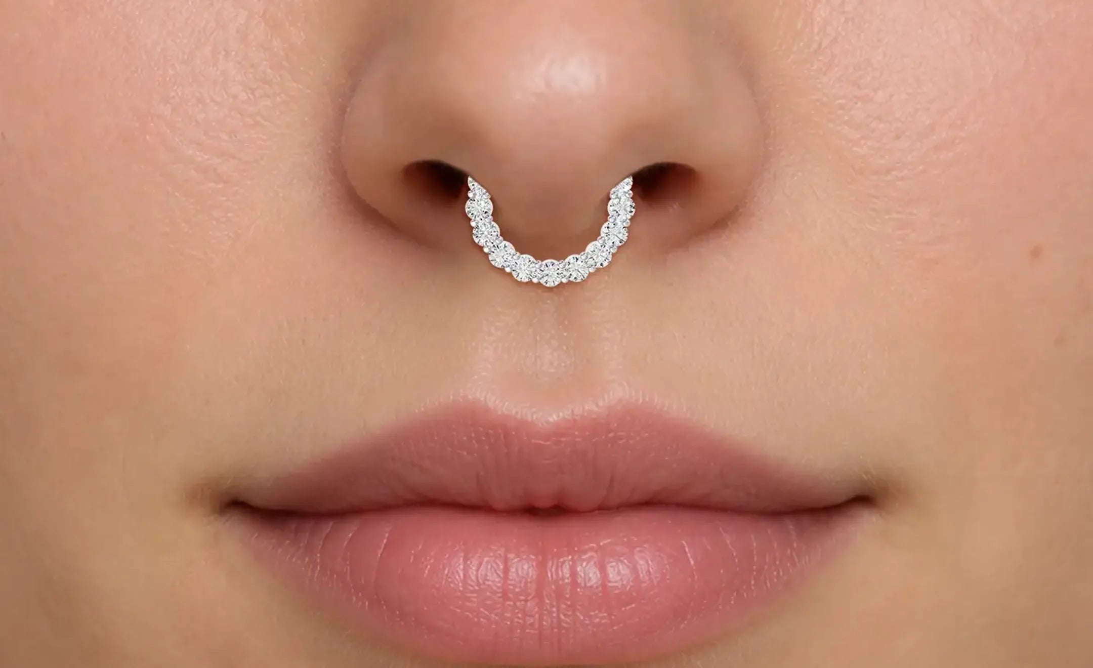 A close-up of a person's nose wearing diamond nose ring set with diamonds in the septum 